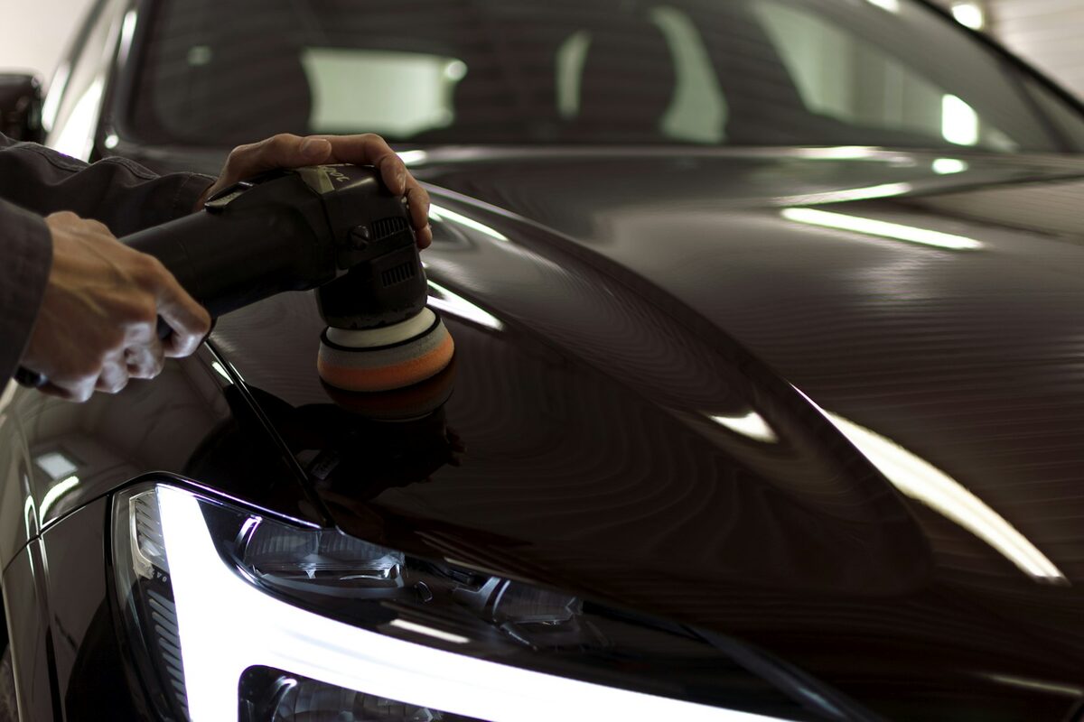 Machine polishing the bonnet of a dark car