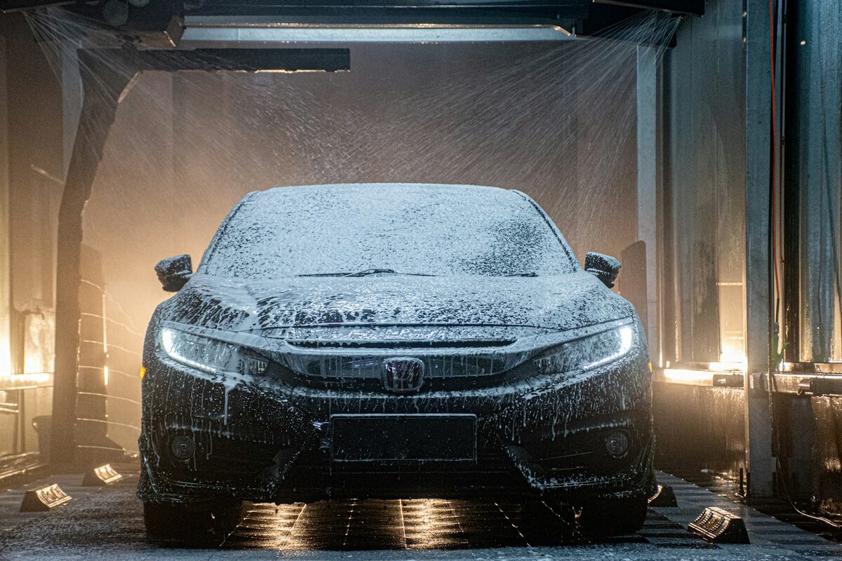 A car covered in snow foam in a wash bay