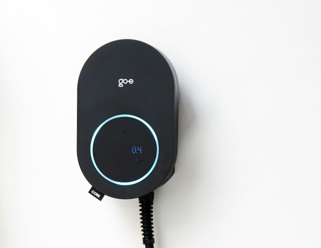 A wall-mounted electric car charger beside a driveway