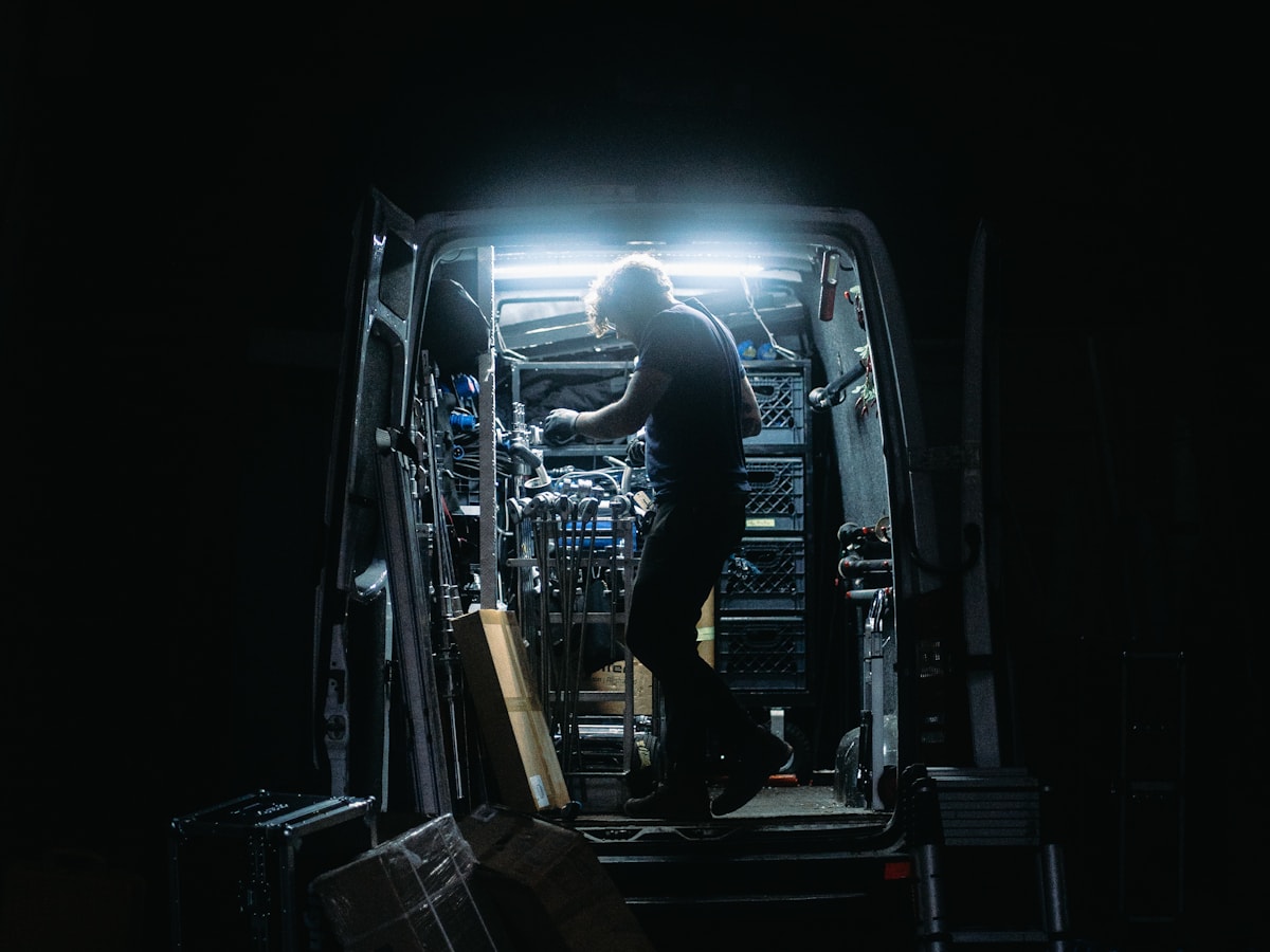 An electrician's van at night, back doors open and the load bay lit up on a call-out